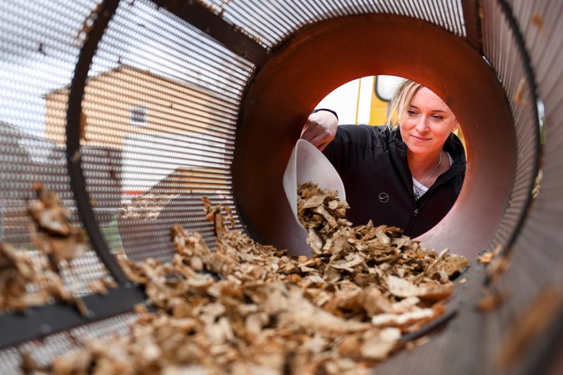 Frau siebt Hackschnitzel im Trommelsieb.