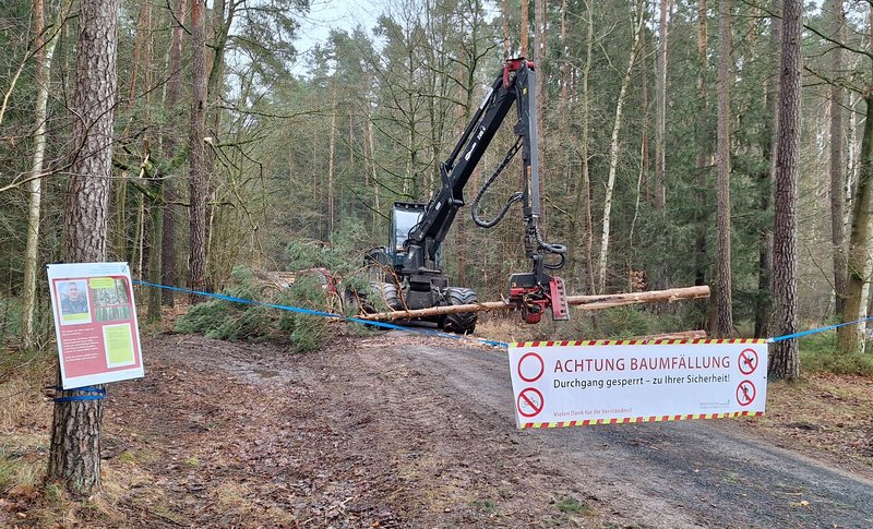 Harvester auf Forstweg hinter einem Absperrbanner
