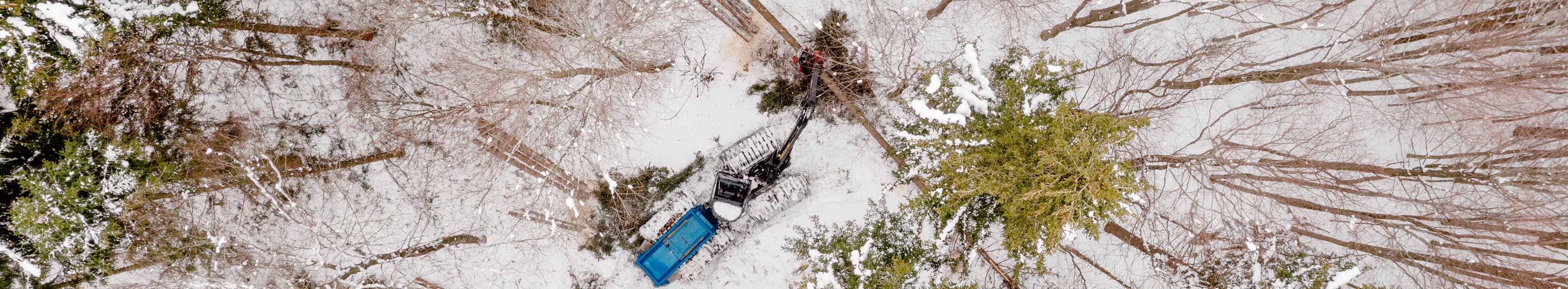 Harvester in a snowy forest filmed from above with a drone