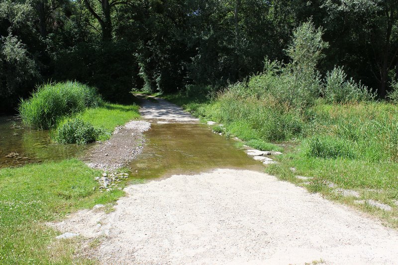 Furt als naturnahe Wegequerung: Das Wasser fließt breitflächig über den Weg ab und vermindert so Abflussbeschleunigung und Erosion.