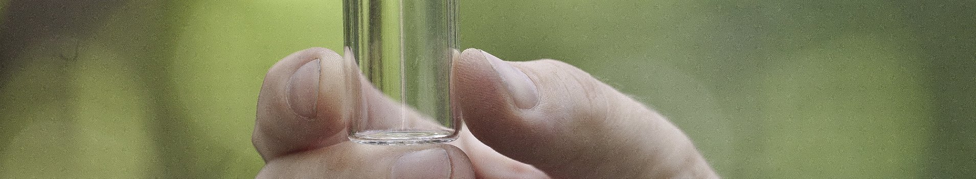Hand in Großaufnahme hält ein Reagenzglas mit Kohlenstoff