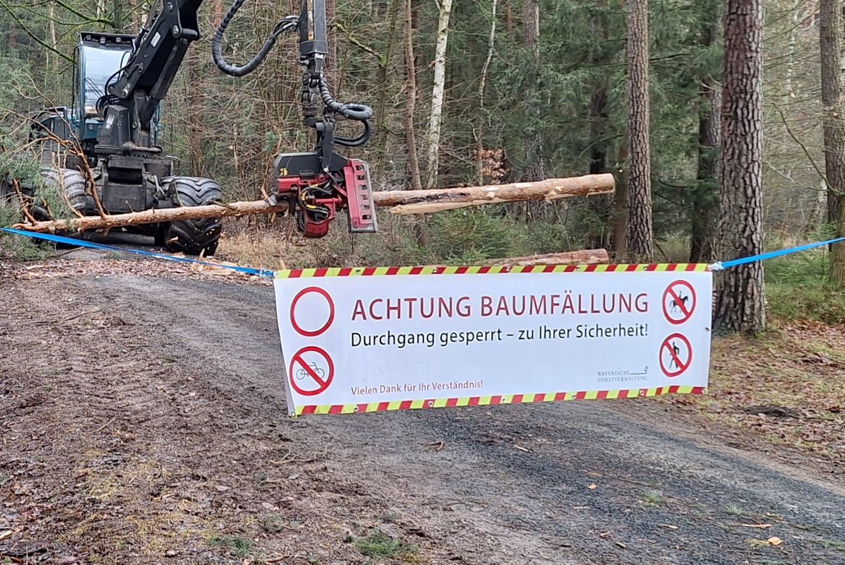 Harvester auf Forstweg hinter einem Absperrbanner