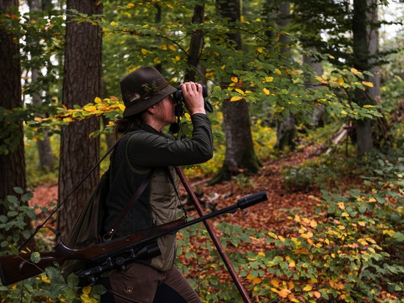 Person mit Jagdequipment steht im Wald 