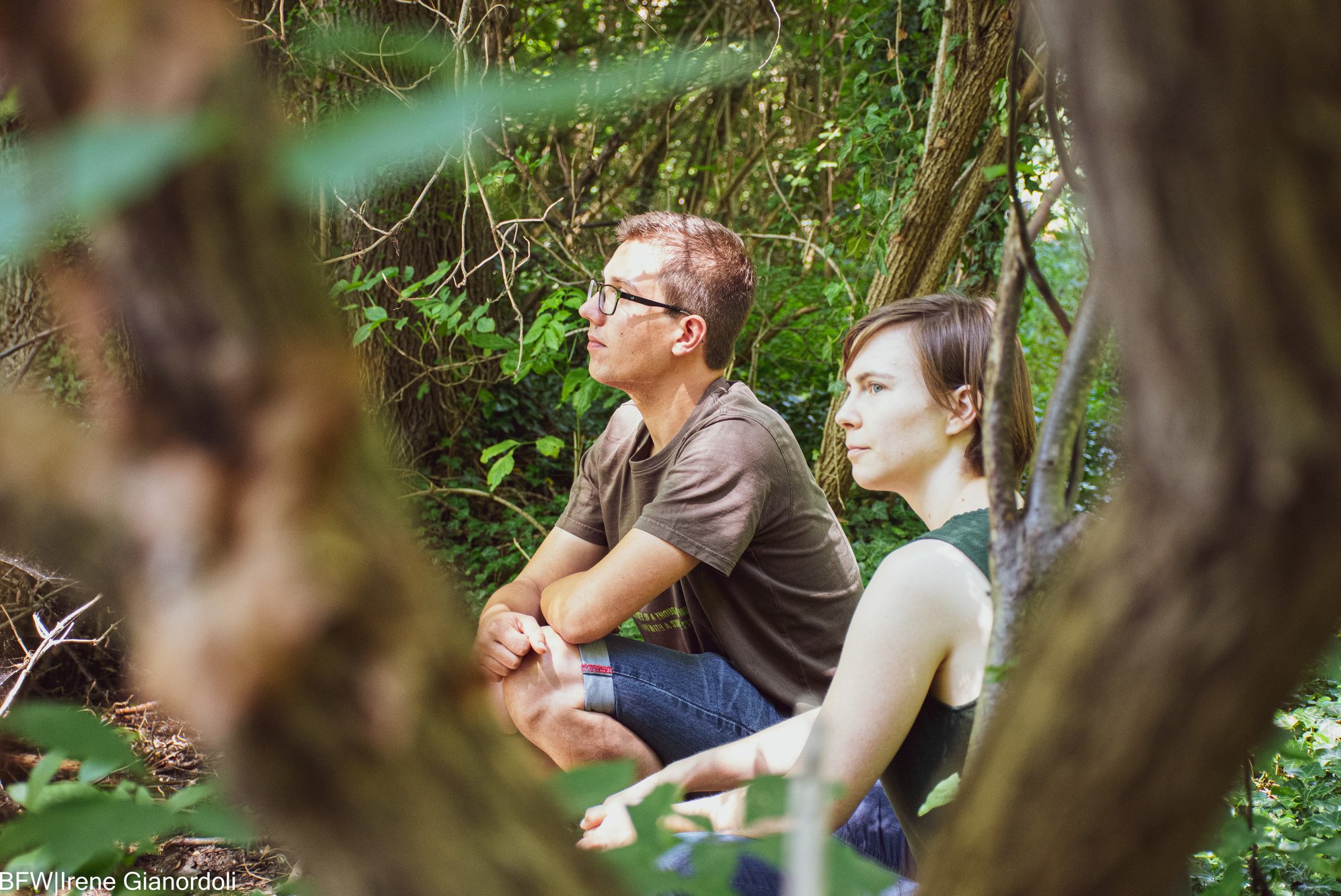 Zwei Personen, die in der Hocke im Wald sitzen