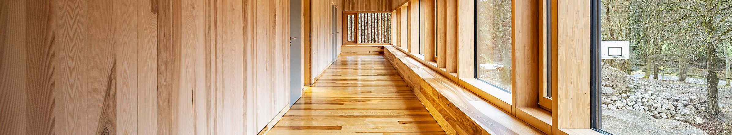 lichter Gang in einem modernen Holzhaus mit einer großen Fensterfront