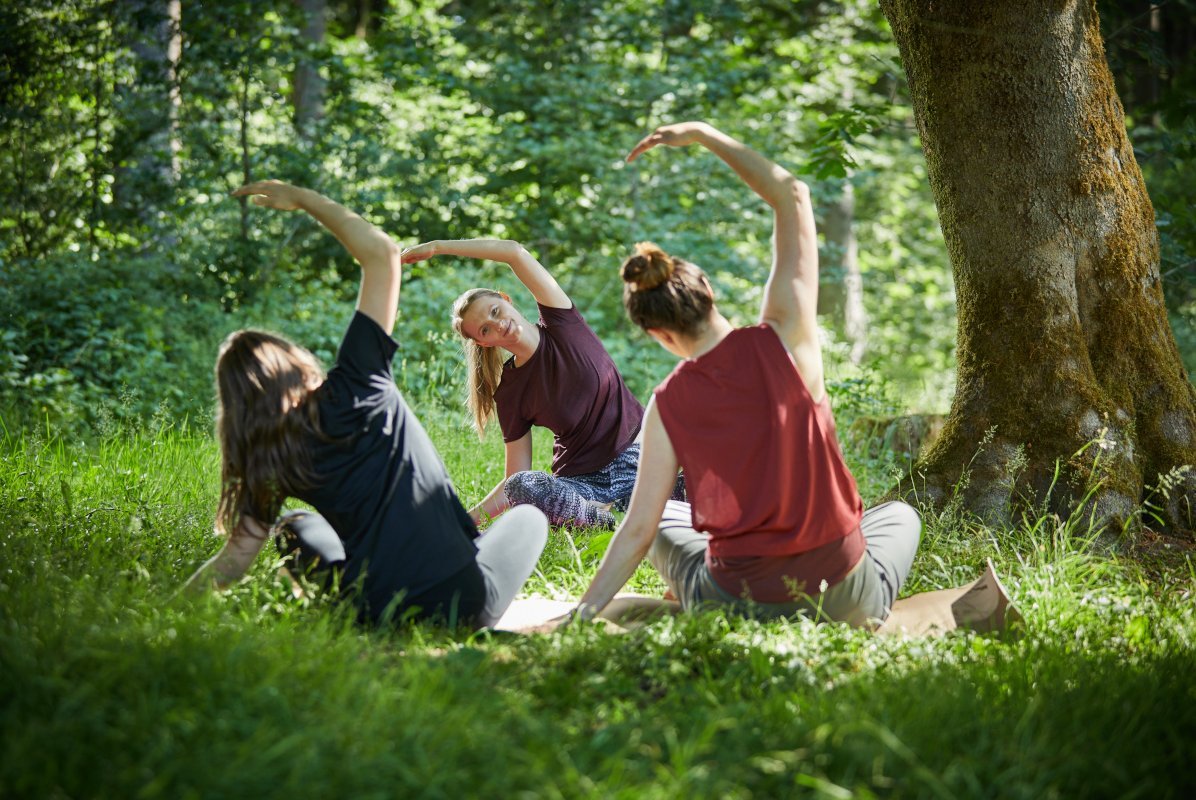 Drei Frauen machen Yogaübungen im Wald