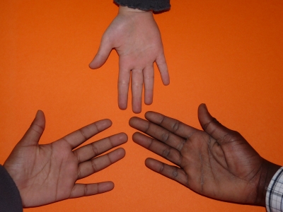 Drei Hände treffen sich auf einer orangenen Oberfläche