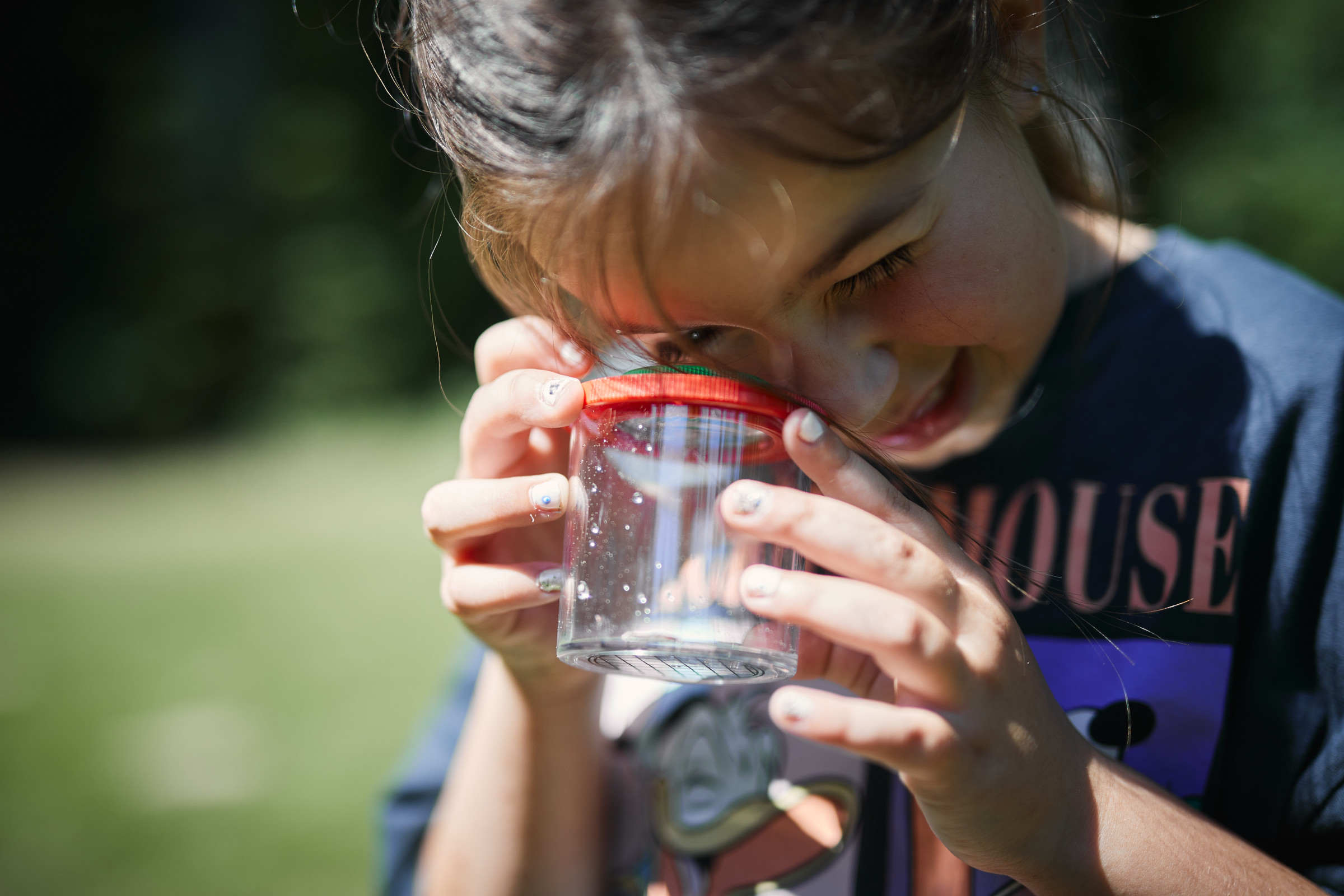 Kind blickt in eine Becherlupe